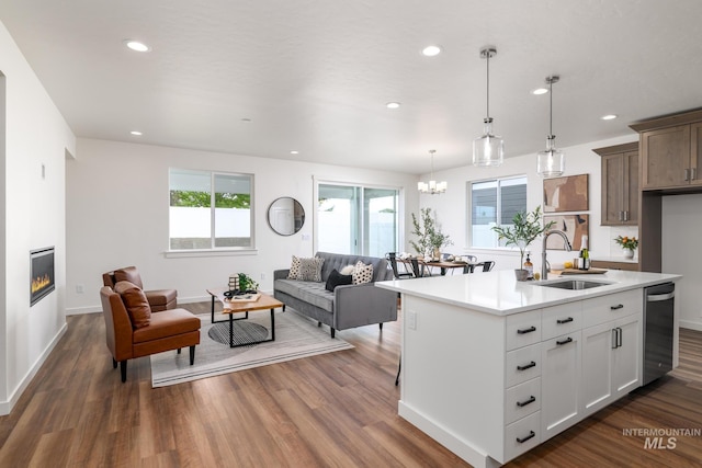 kitchen with sink, dark wood-type flooring, decorative light fixtures, a kitchen island with sink, and white cabinets