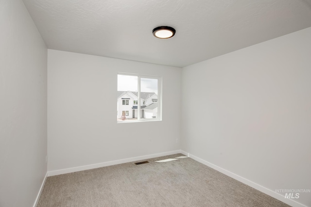 spare room with carpet and a textured ceiling