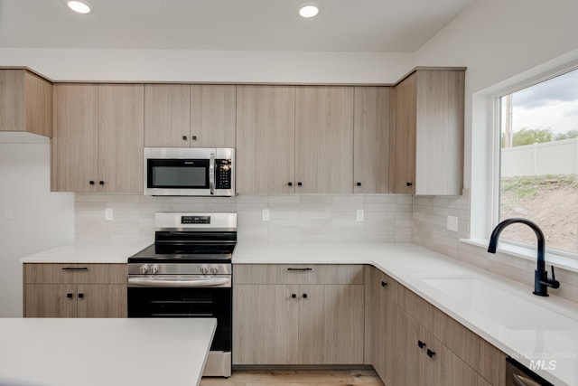 kitchen featuring light brown cabinetry, appliances with stainless steel finishes, sink, and decorative backsplash