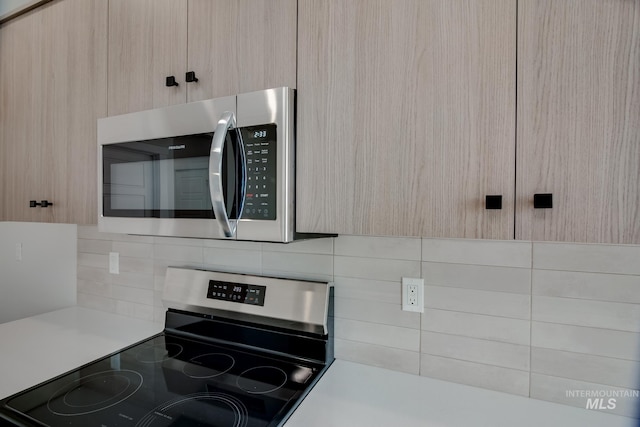 kitchen with tasteful backsplash, appliances with stainless steel finishes, and light brown cabinets