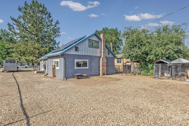 1025 W Galloway Ave, Weiser, ID 83672 - rear view of house with concrete block siding, a chimney, an outdoor structure, and roof mounted solar panels