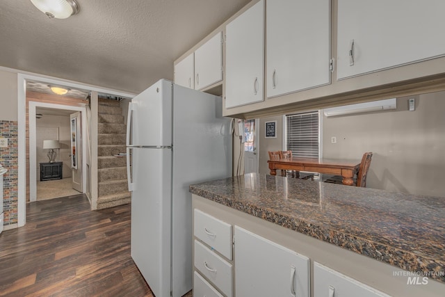 1025 W Galloway Ave, Weiser, ID 83672 - kitchen with freestanding refrigerator, dark wood-style flooring, white cabinets, dark countertops, and a textured ceiling