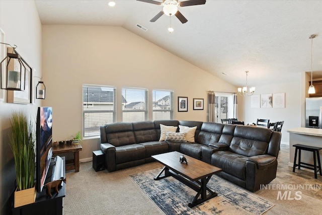 carpeted living room with ceiling fan with notable chandelier and high vaulted ceiling