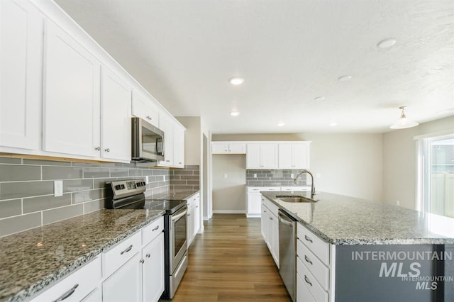 3749 E Rock Falls St, Nampa, ID 83686 - kitchen with white cabinets, backsplash, a sink, a kitchen island with sink, and appliances with stainless steel finishes