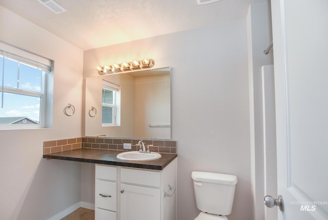 3749 E Rock Falls St, Nampa, ID 83686 - bathroom with decorative backsplash, toilet, vanity, and visible vents