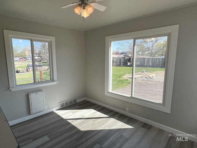 unfurnished room featuring wood finished floors, baseboards, a ceiling fan, and visible vents