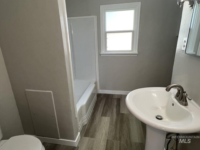 bathroom with a bathing tub, toilet, wood finished floors, a sink, and walk in shower