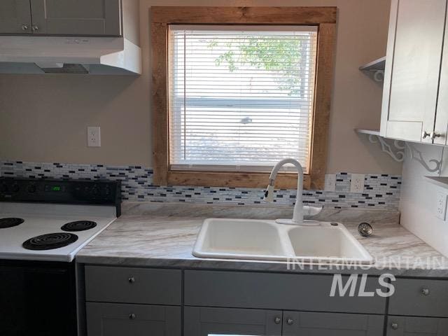 kitchen with a sink, electric range oven, backsplash, and under cabinet range hood
