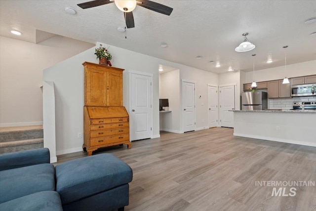 2312 E Spice Loop Unit 3, Nampa, ID 83687 - living room featuring light wood-type flooring, baseboards, a ceiling fan, stairway, and a textured ceiling