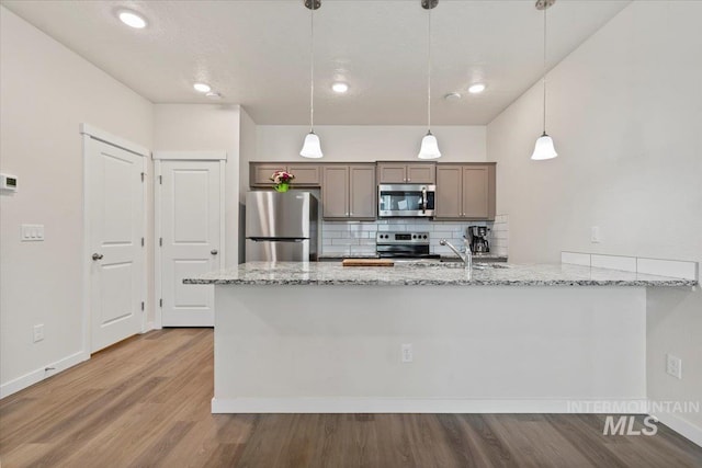 2312 E Spice Loop Unit 3, Nampa, ID 83687 - kitchen with stainless steel appliances, wood finished floors, light stone countertops, backsplash, and a sink