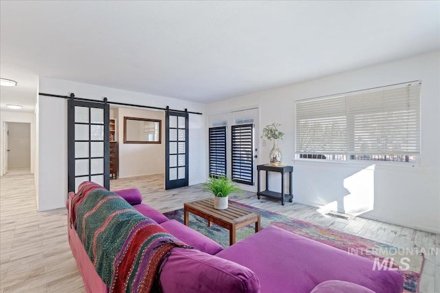 living room featuring light hardwood / wood-style floors, a barn door, and french doors