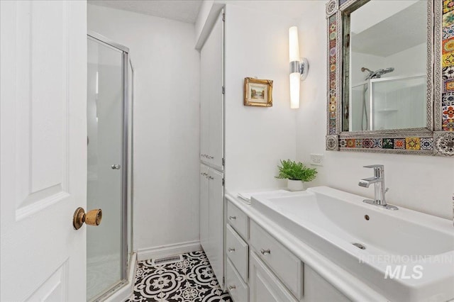 bathroom with tile patterned flooring, vanity, and walk in shower