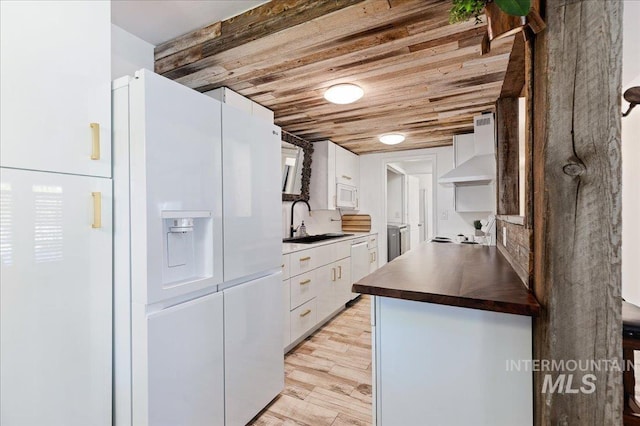 kitchen with wall chimney exhaust hood, sink, wood ceiling, white appliances, and white cabinets