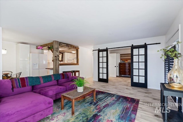 living room with light hardwood / wood-style flooring, a barn door, and french doors