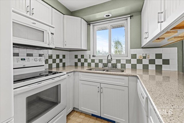 1267 NW Beaman St, Mountain Home, ID 83647 - kitchen featuring white appliances, a sink, backsplash, white cabinetry, and light stone counters