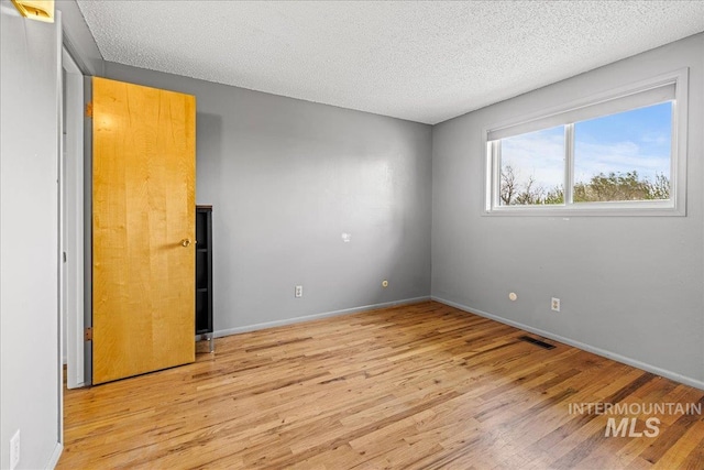 1267 NW Beaman St, Mountain Home, ID 83647 - unfurnished room featuring light wood-style flooring, a textured ceiling, and baseboards