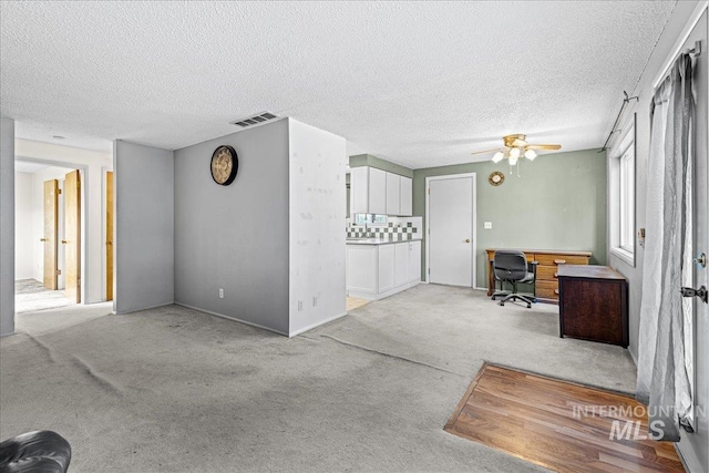 1267 NW Beaman St, Mountain Home, ID 83647 - unfurnished living room featuring light carpet, a desk, ceiling fan, and a textured ceiling