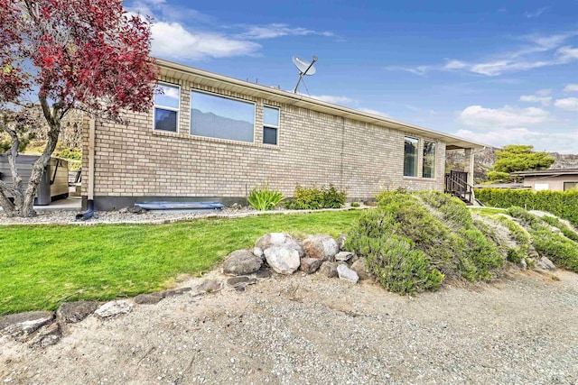 view of home's exterior featuring brick siding and a lawn