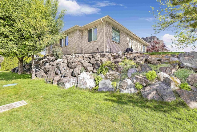 view of property exterior with a lawn and brick siding