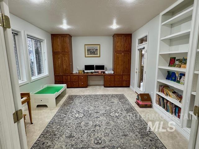 office space with built in desk, a textured ceiling, and built in features