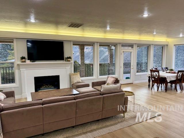 living room with recessed lighting, visible vents, a fireplace, and light wood finished floors