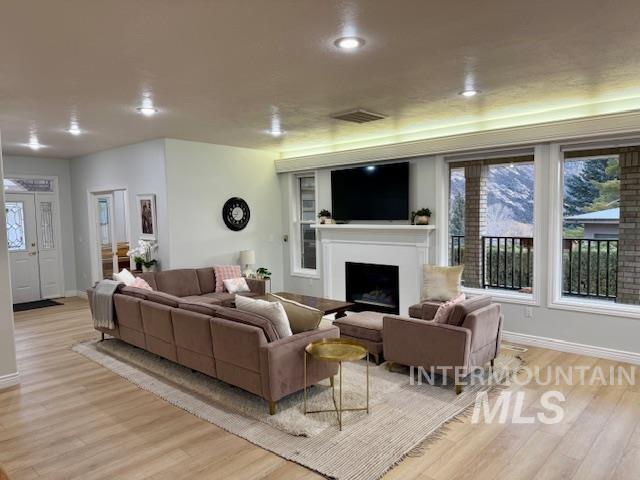 living room featuring visible vents, baseboards, light wood-style floors, and a fireplace