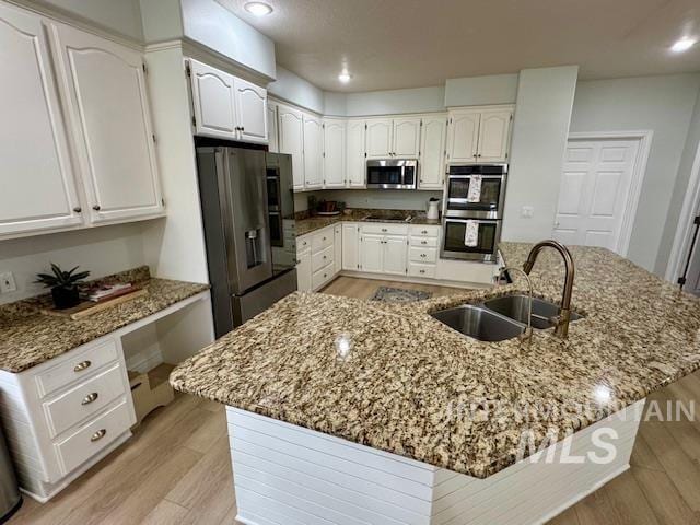 kitchen featuring white cabinetry, light wood-style flooring, appliances with stainless steel finishes, built in study area, and a sink