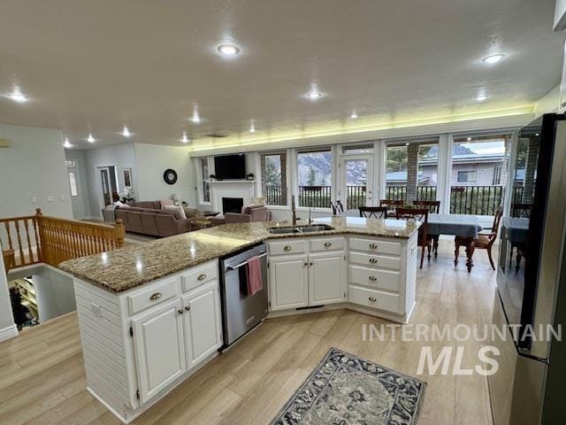 kitchen with a sink, freestanding refrigerator, white cabinetry, light wood-style floors, and dishwasher