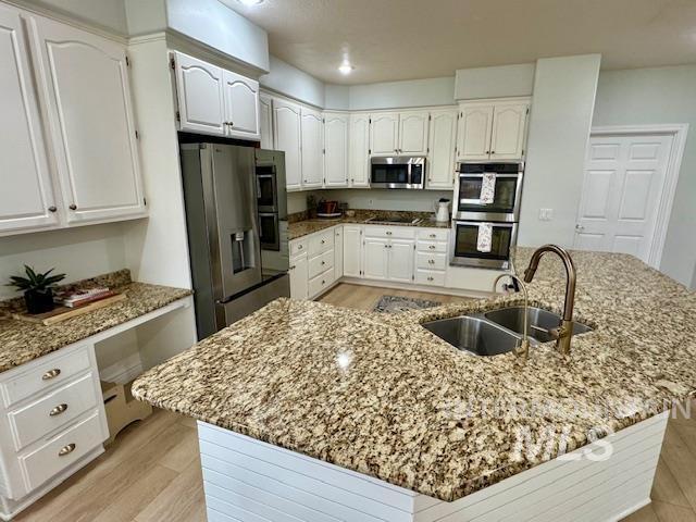 kitchen featuring a sink, white cabinets, built in desk, and stainless steel appliances