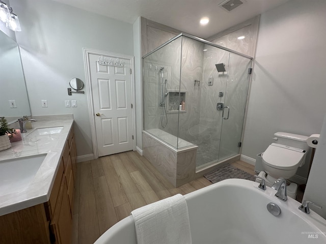 bathroom with a sink, toilet, wood finished floors, and a shower stall