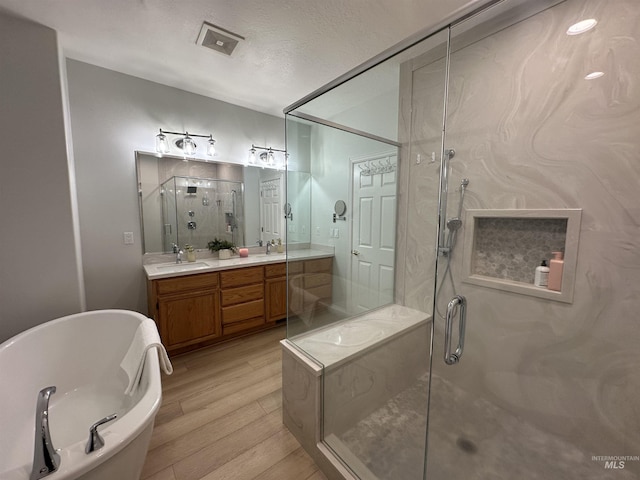 bathroom featuring a sink, a shower stall, wood finished floors, and a freestanding tub