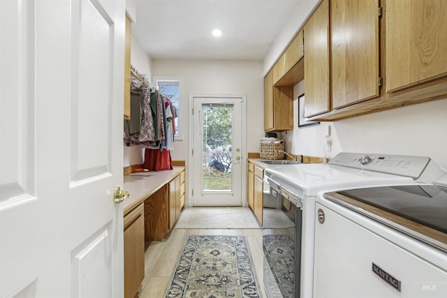 clothes washing area featuring washer and dryer, cabinet space, and a sink