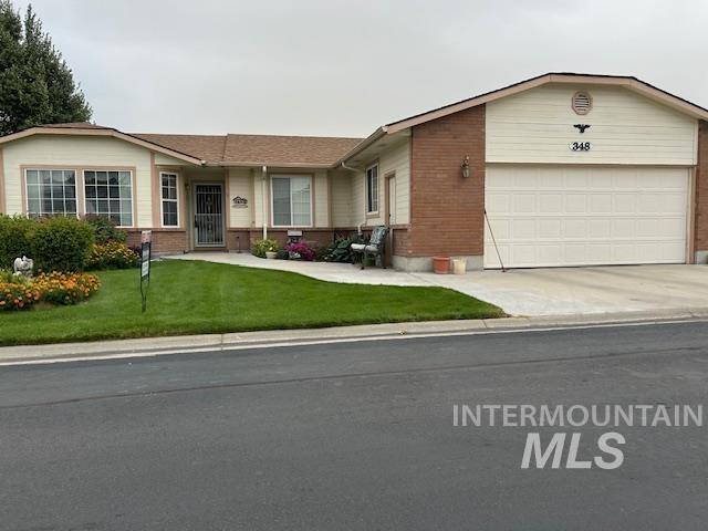 single story home featuring a garage, driveway, brick siding, and a front yard