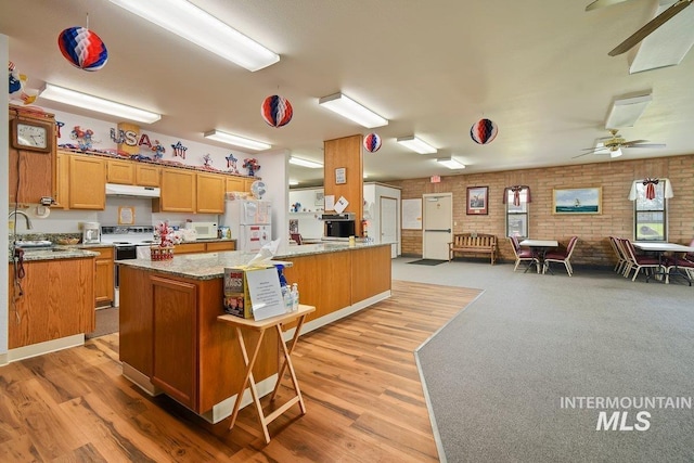1100 Burnett Dr Unit 348, Nampa, ID 83651 - kitchen with under cabinet range hood, a peninsula, white appliances, brick wall, and open floor plan
