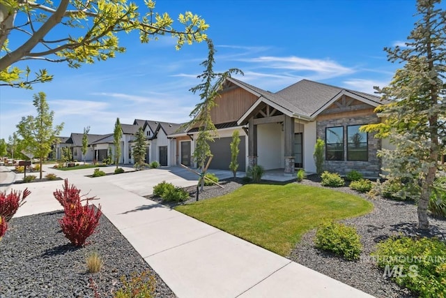 view of front of home with driveway, stone siding, an attached garage, and a front yard