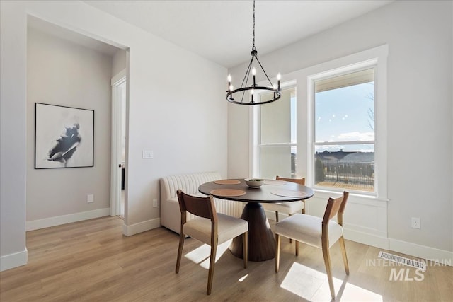 dining room with a chandelier, light wood-style flooring, and baseboards
