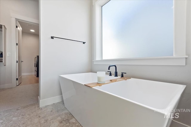 full bath with a freestanding bath and baseboards