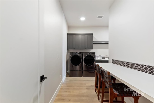 laundry room featuring washer and clothes dryer, cabinet space, light wood-style floors, recessed lighting, and baseboards
