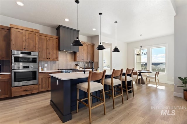 kitchen with stainless steel appliances, backsplash, light countertops, light wood-style floors, and recessed lighting