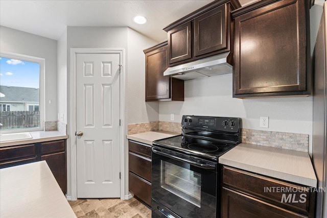 kitchen featuring light countertops, black / electric stove, dark brown cabinets, and under cabinet range hood