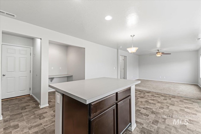 kitchen with a center island, pendant lighting, light countertops, visible vents, and dark brown cabinets