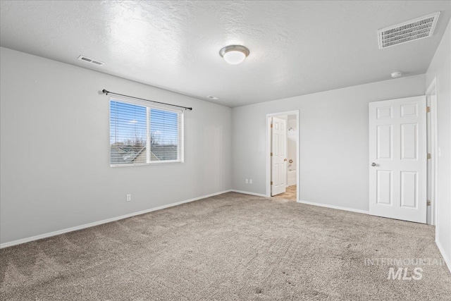 carpeted empty room featuring a textured ceiling, visible vents, and baseboards