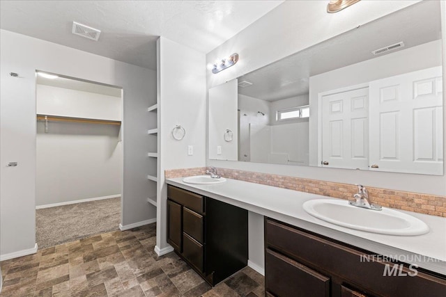 full bathroom featuring double vanity, a spacious closet, visible vents, and a sink