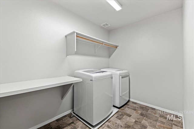 clothes washing area with visible vents, stone finish floor, laundry area, independent washer and dryer, and baseboards