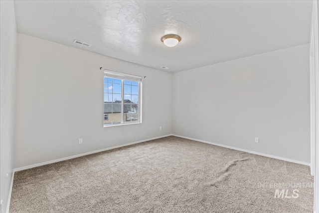 empty room featuring baseboards, visible vents, a textured ceiling, and carpet flooring