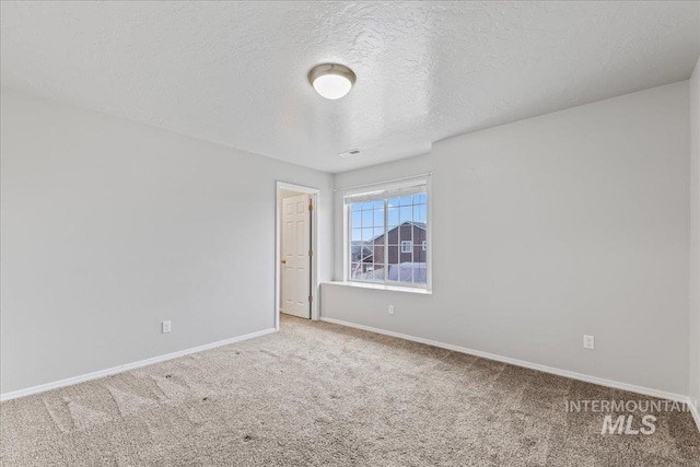 empty room featuring carpet flooring, a textured ceiling, and baseboards