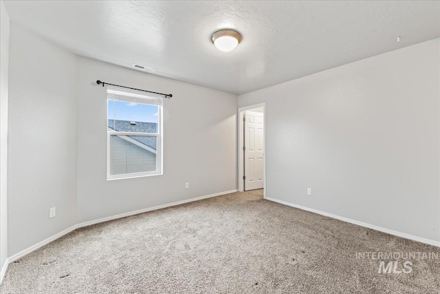 empty room featuring baseboards, a textured ceiling, visible vents, and carpet flooring