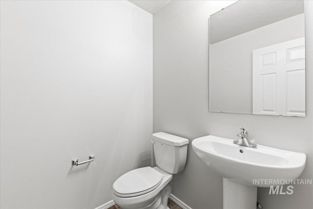 bathroom featuring baseboards, a sink, and toilet