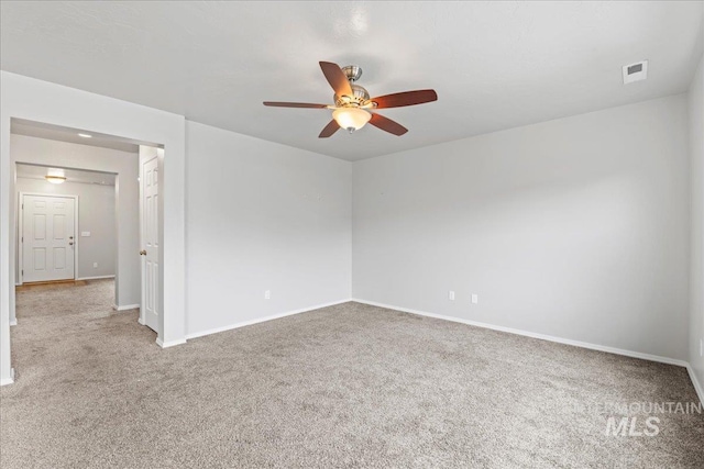 carpeted empty room featuring ceiling fan, visible vents, and baseboards