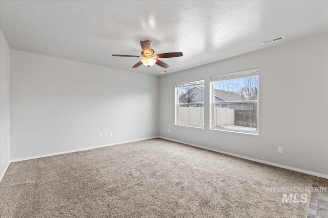 empty room featuring carpet, visible vents, and baseboards